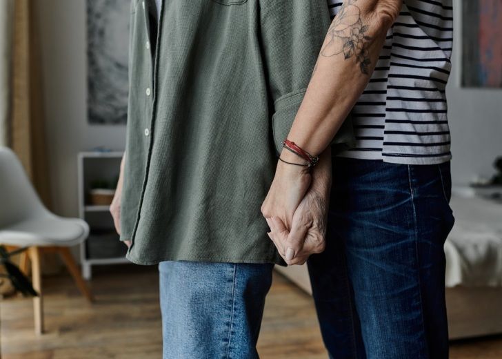 A mature lesbian couple holds hands and hugs in their modern apartment.